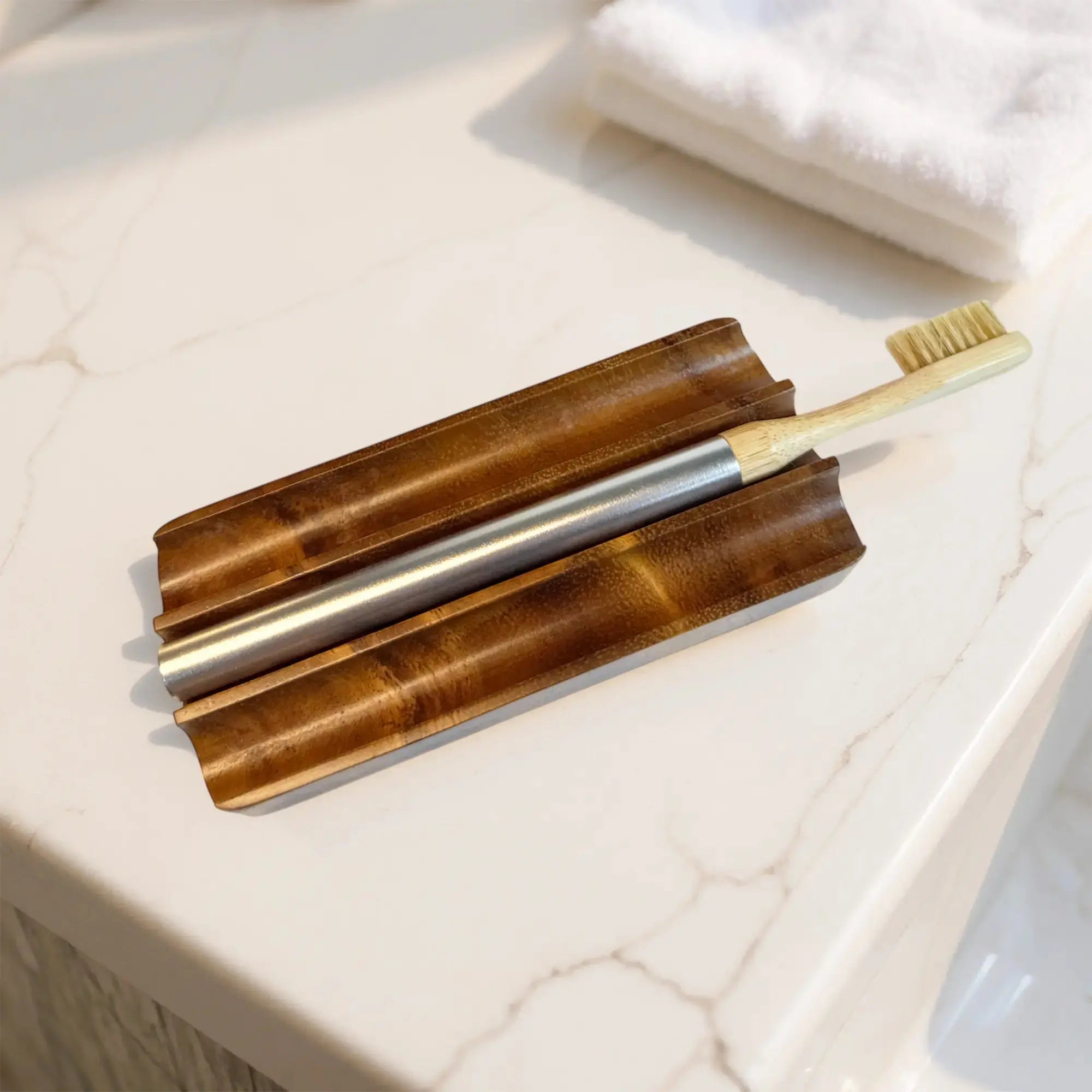 Nathan and Sons Boar's Hair Toothbrush Kit featuring boar's hair bristles, a bamboo neck and an aluminum handle resting on a sculpted wooden holder atop a marble bathroom countertop.