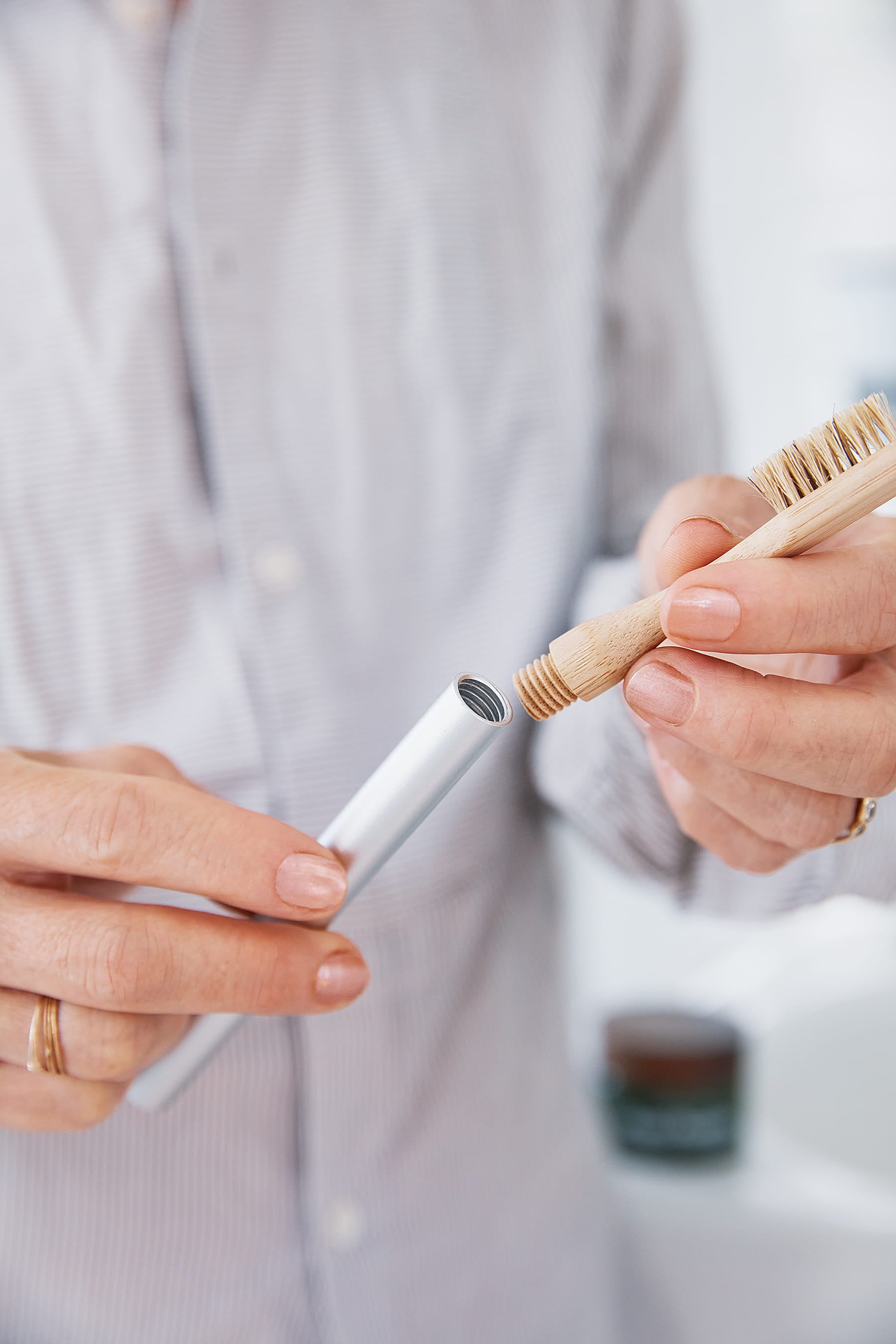 Person assembling a Boars Hair Bamboo toothbrush head and Nathan and sons Aluminum Toothbrush handle by screwing them together