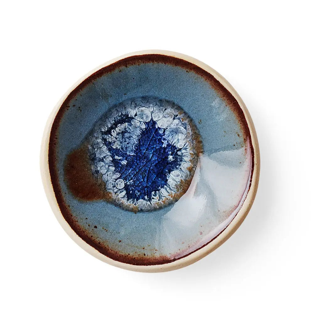 Top view of Underbrush handmade ceramic gum dish with a batik blue glaze flowing pattern
