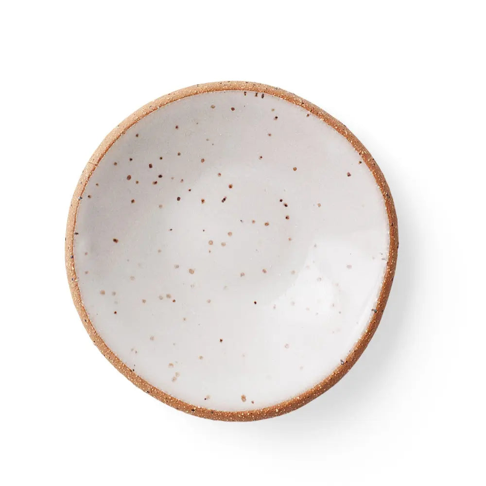 Top-down view of a handmade ceramic gum dish in a Speckled White glaze, featuring a smooth white surface with scattered brown speckles and a clay rim