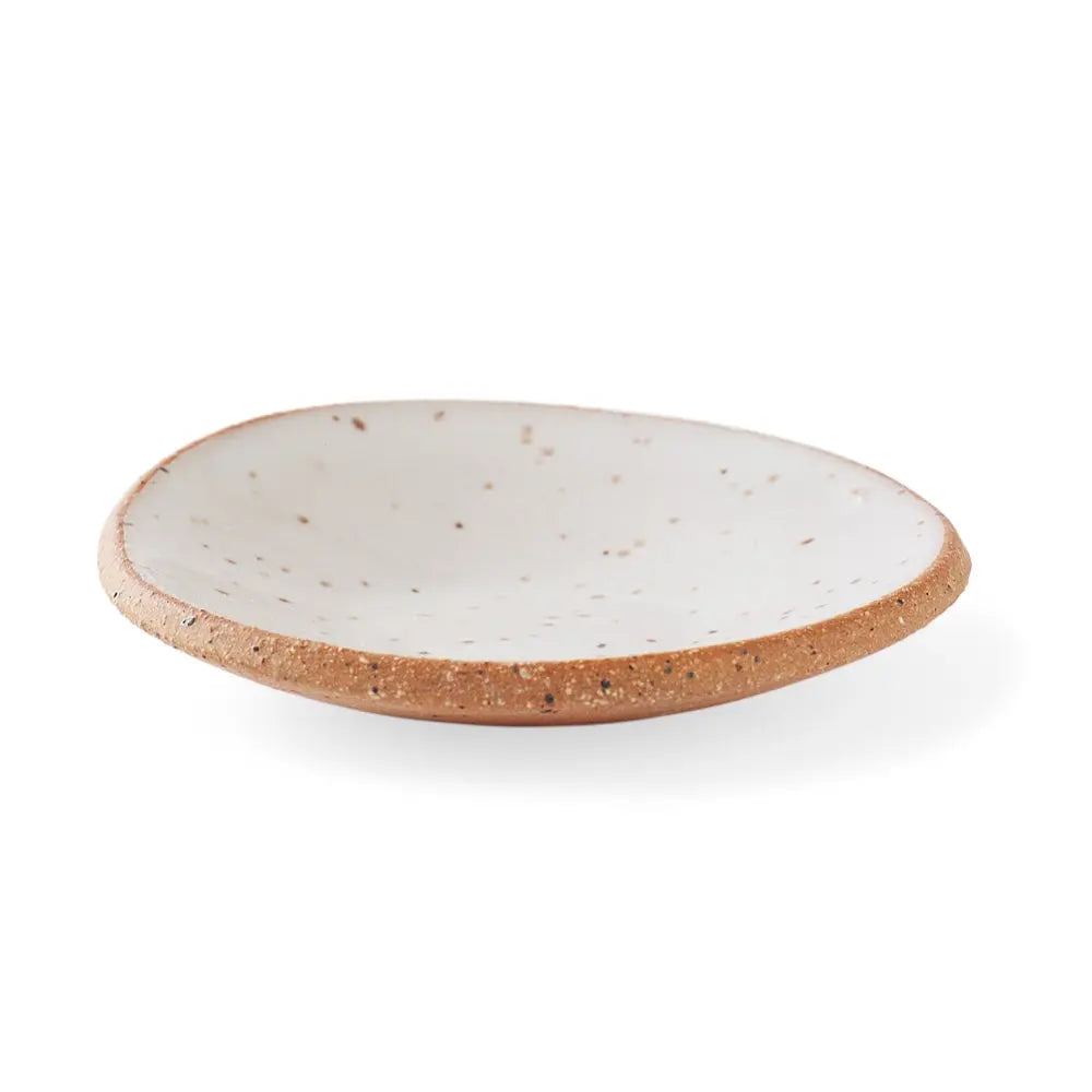 Frontal view of a handmade ceramic gum dish in a Speckled White glaze, featuring a smooth white surface with scattered brown speckles and a clay rim