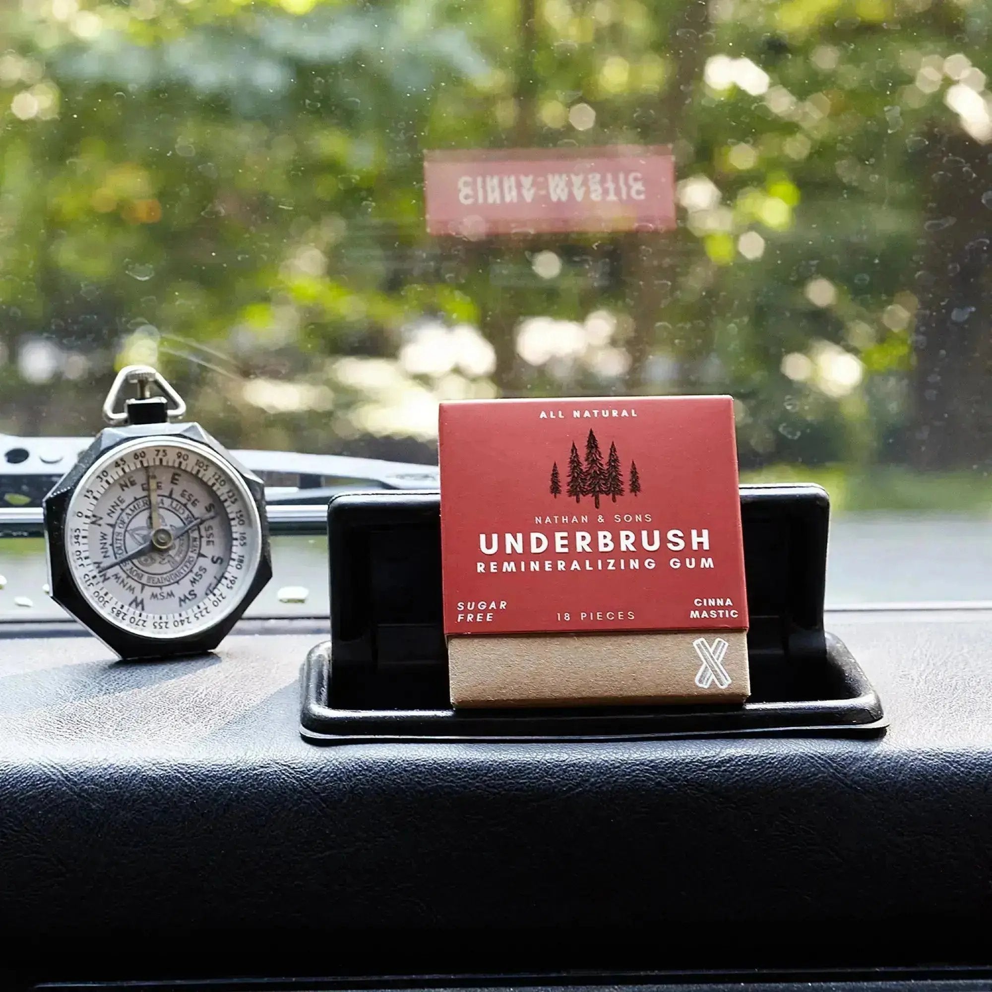 Underbrush Cinna Mastic Remineralizing Gum on car dashboard with vintage compass