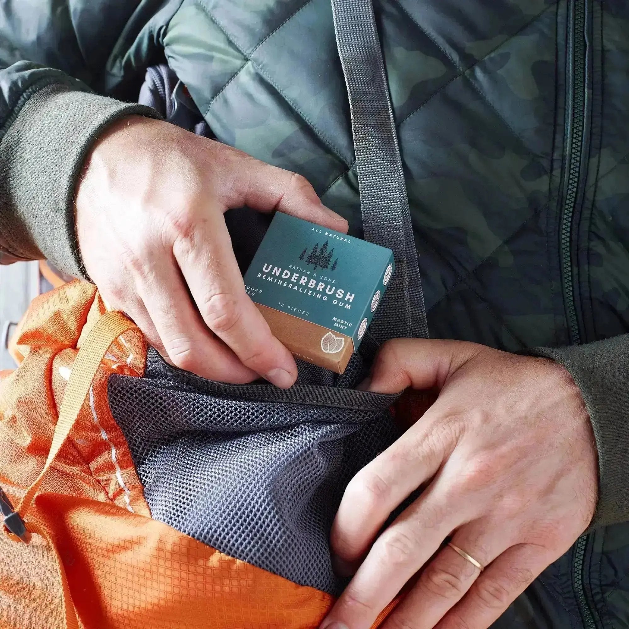Person placing Underbrush remineralizing gum into orange backpack