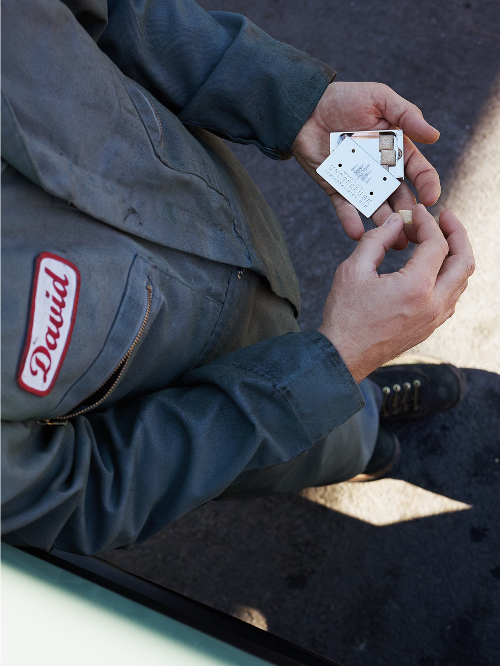 Mechanic holding Underbrush Stainless Slide Snap Gum Case with gum pieces.