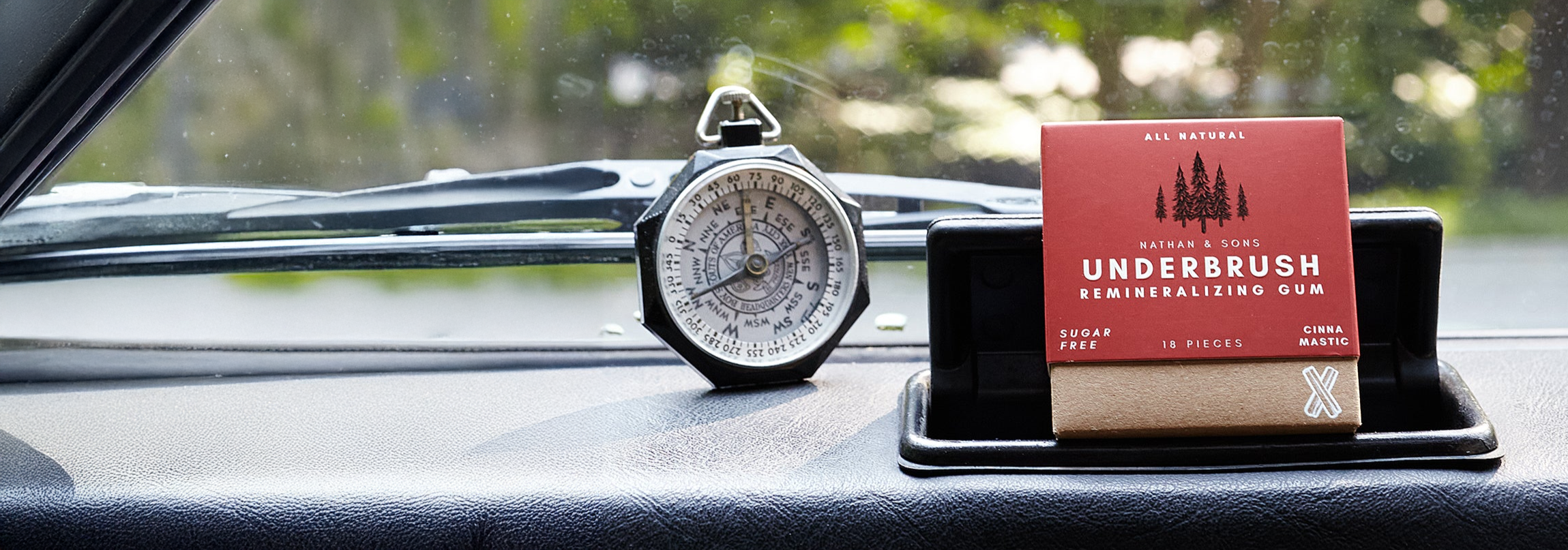 Underbrush Cinna Mastic Remineralizing Gum on car dashboard with vintage compass