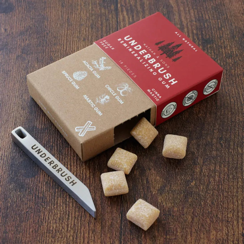 Underbrush Cinna-Mastic remineralizing gum with gum pieces showing next to the minimalist multi-tool key-chain on a wooden table