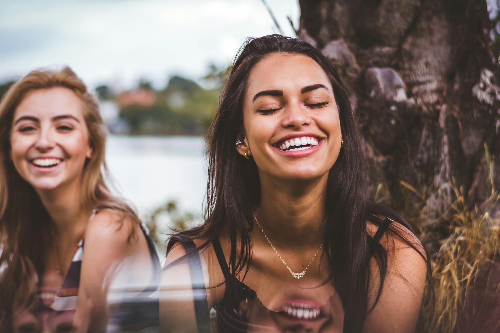 Two young women smiling outdoors with healthy white teeth